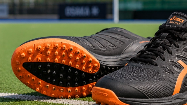 Chaussures de hockey sur gazon avec semelle à picots posées sur un terrain synthétique